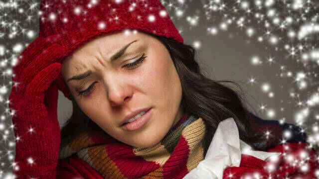 Sick Mixed Race Woman Wearing Winter Hat and Gloves with a Tissue and Snow Effect Surrounding Her.