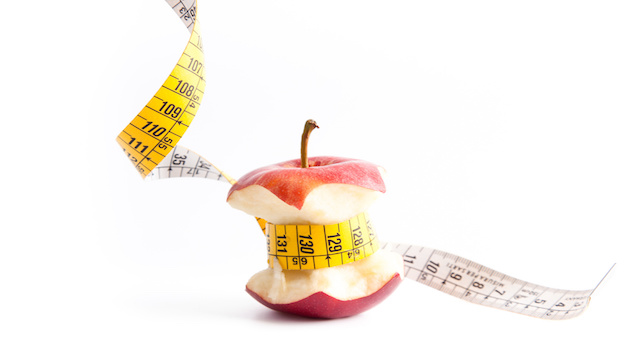 Manzana mordida con una cinta metrica