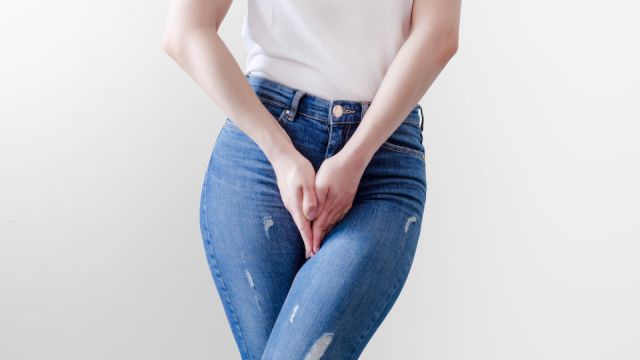 Young woman in jeans standing with her hands between legs