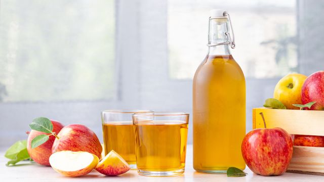 Healthy organic food. Apple cider vinegar or juice in glass bottle and fresh red apples on a light background.