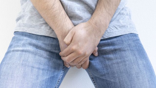 股間を押さえる男性