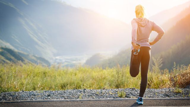 Running stretching. Athlete at the top of the mountain.